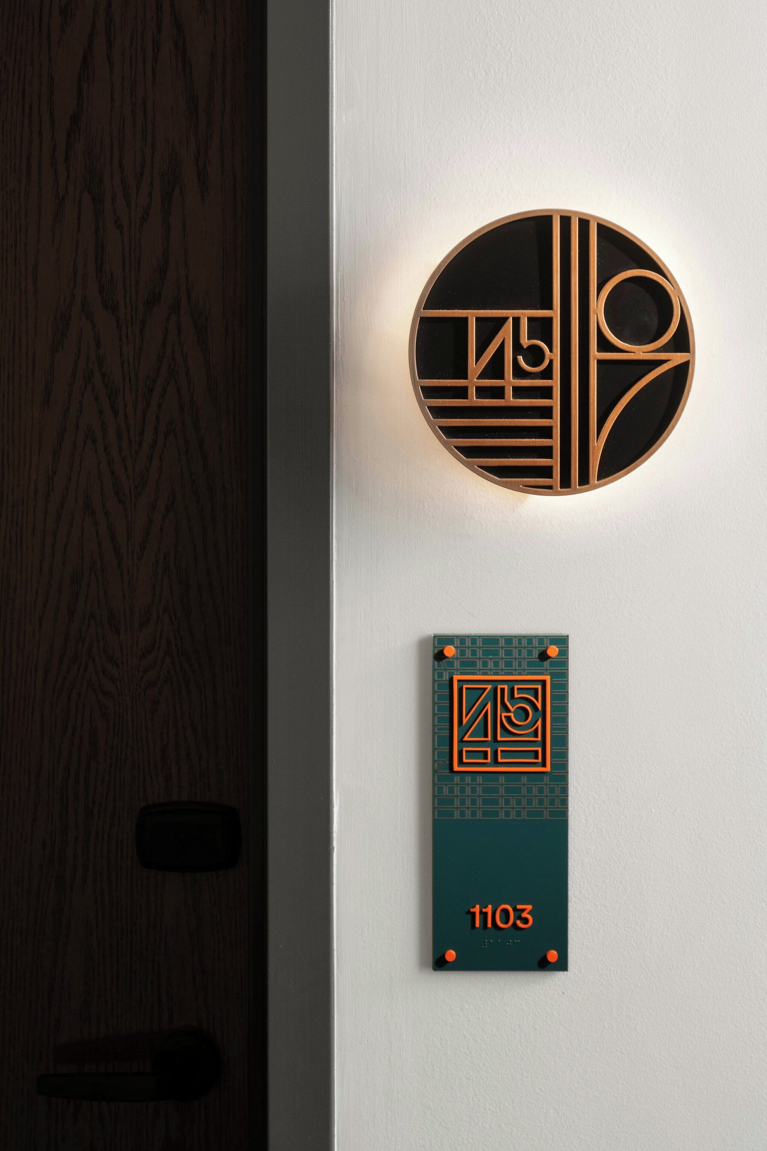 A wall-mounted circular light fixture with geometric patterns and a rectangular plaque with the number 1103.