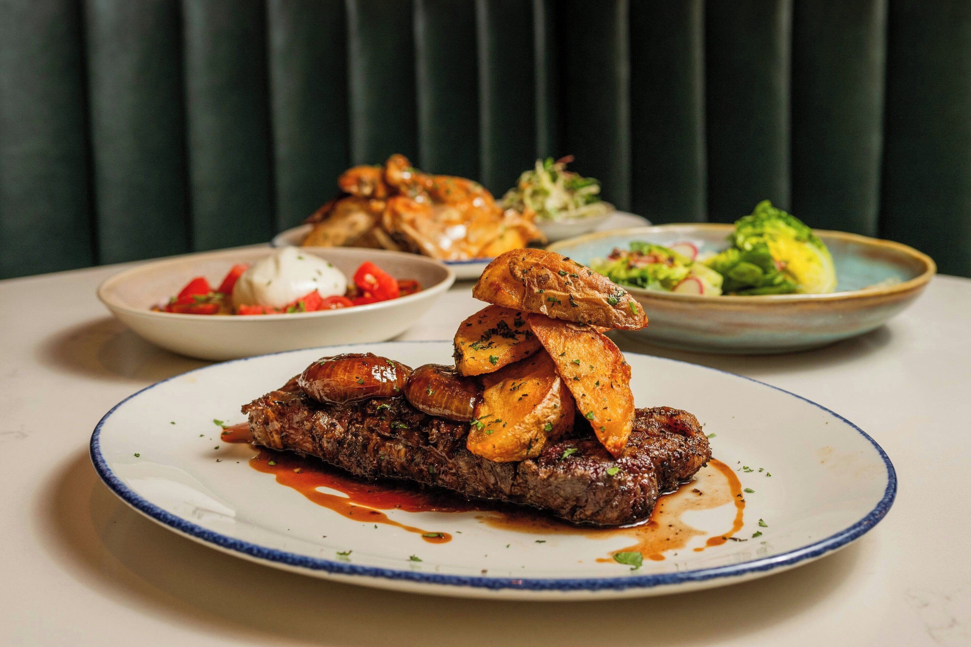 Une assiette de steak accompagnée de pommes de terre rôties et d’une salade.