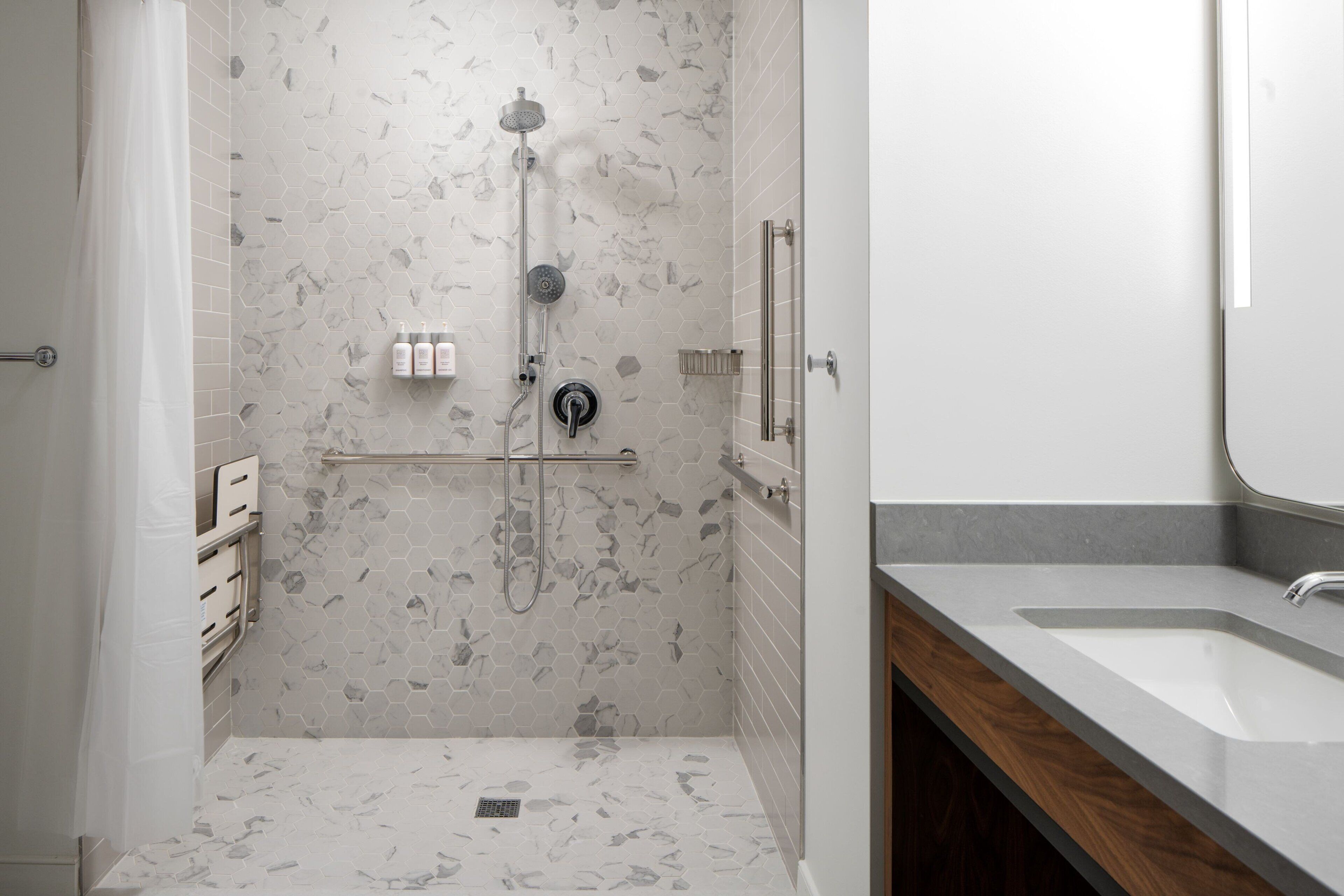A modern bathroom with a shower, a sink, and a mirror.