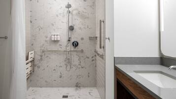 A modern bathroom with a shower, a sink, and a mirror.