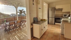 A kitchen with a tiled floor, a refrigerator, a microwave, and a dining area with a table and chairs. - T2 with small pool and beautiful sea view (LES TROIS ILETS)