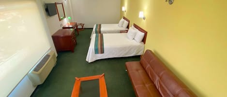 Una habitación de hotel con dos camas, un escritorio, una silla, un sofá y un espejo.