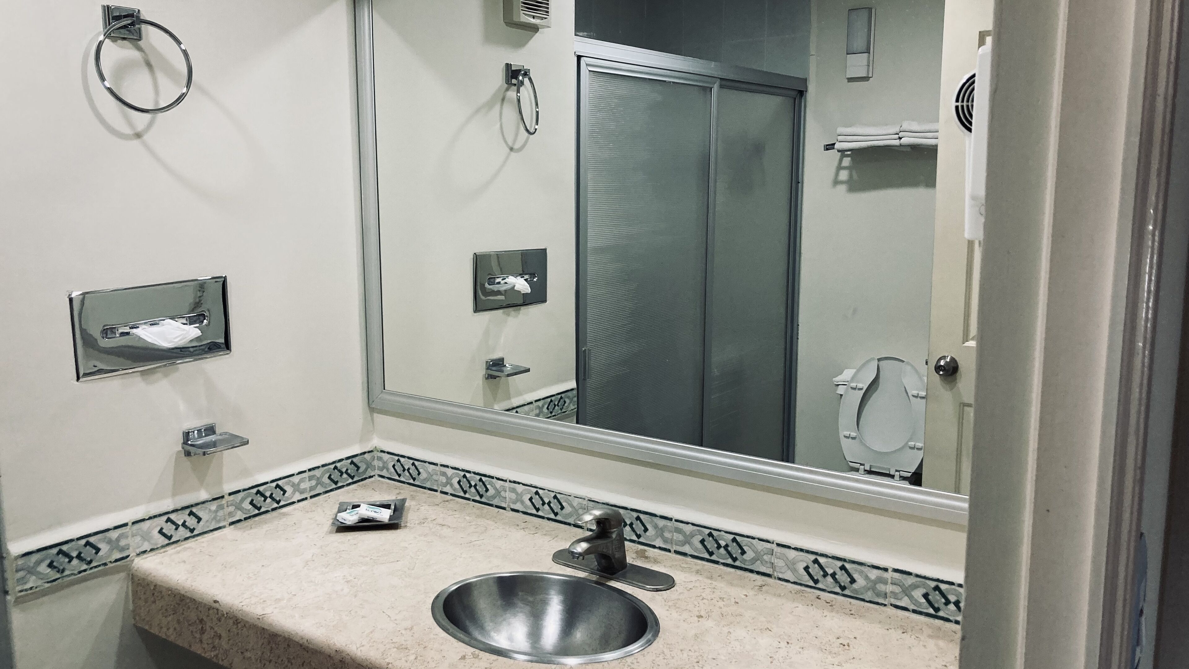 A bathroom with a sink, mirror, towel rack, and toilet.