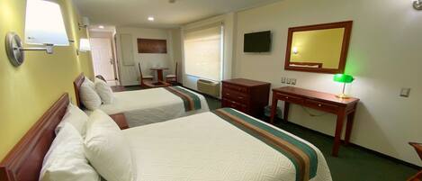 A hotel room with two beds, a desk, a chair, a mirror, and a television on the wall.