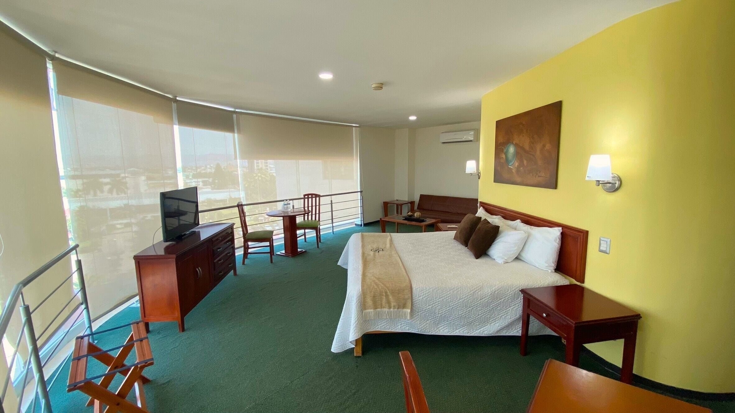 Hotelkamer met een bed, een bureau, een stoel, een televisie en een balkon met uitzicht.