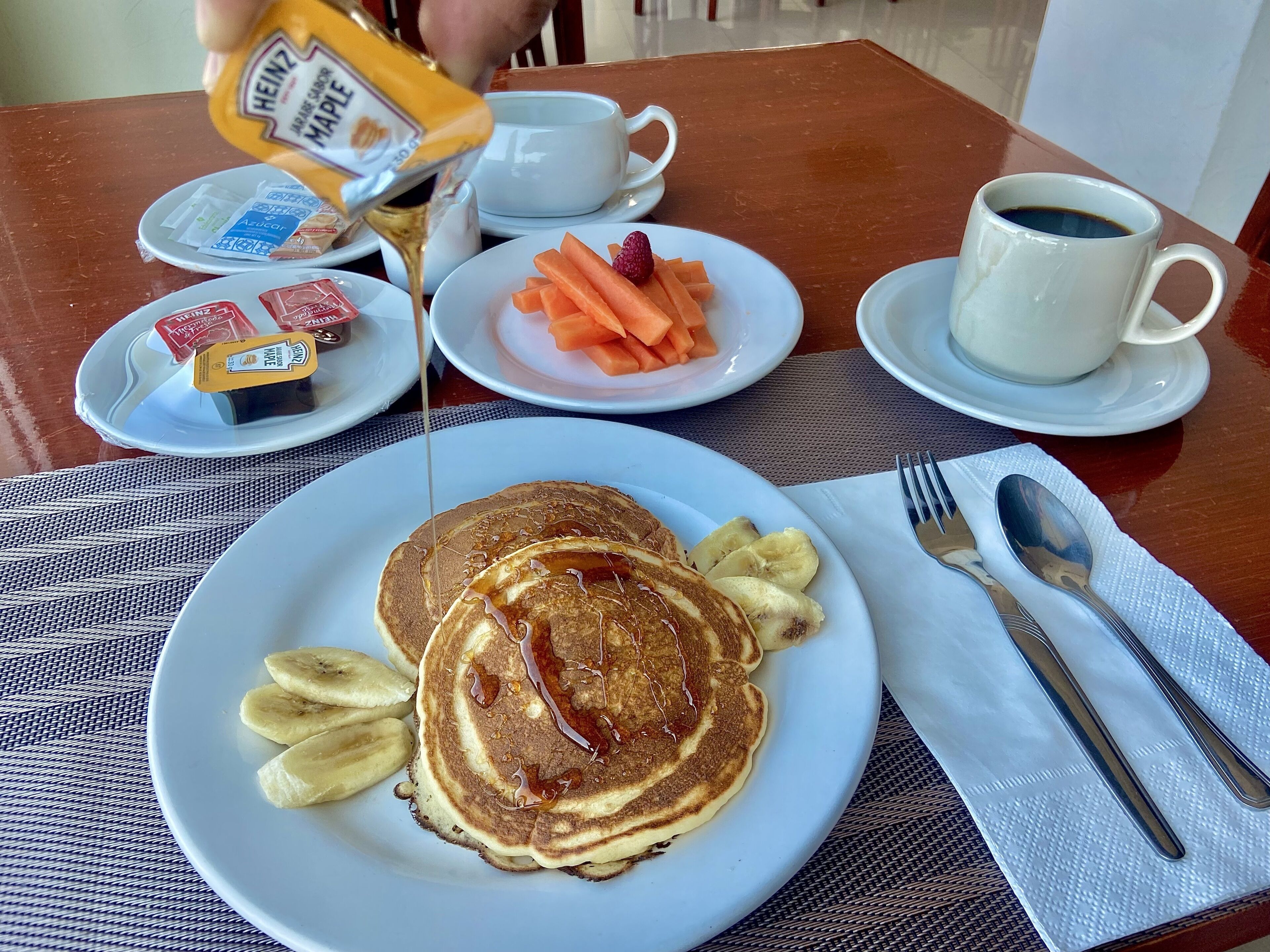 A breakfast setting with pancakes, bananas, and a cup of coffee.