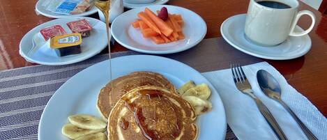 A breakfast setting with pancakes, bananas, and a cup of coffee.