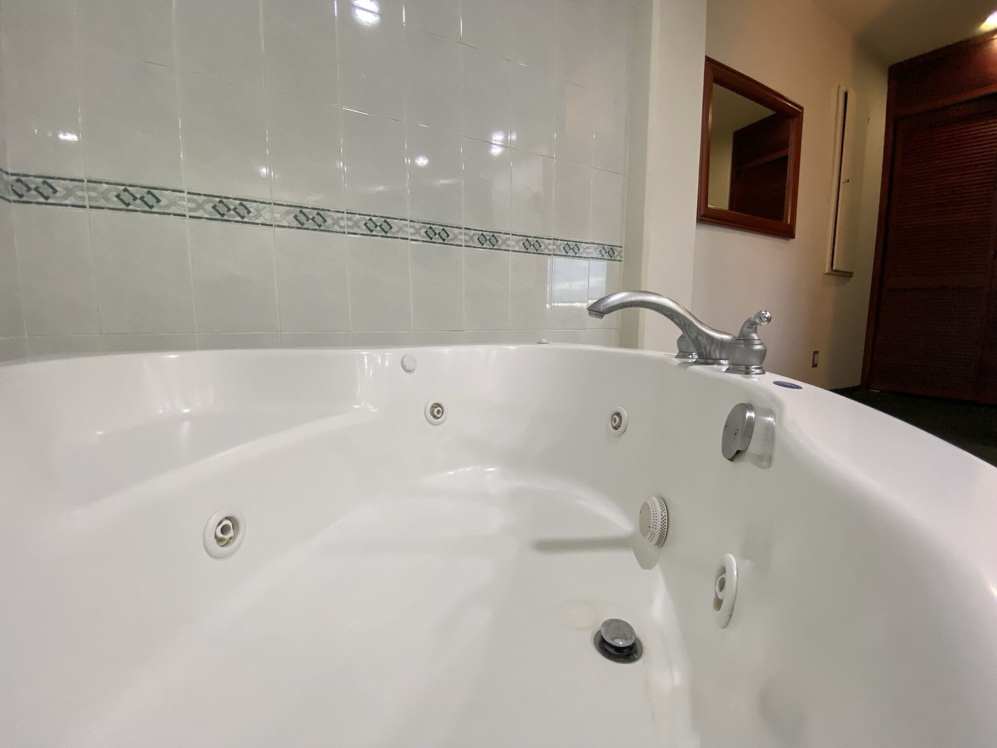 A white bathtub with a modern faucet, a showerhead, and a drain.