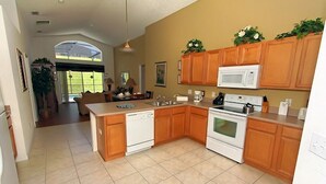 A kitchen with wooden cabinets, a central island, a microwave, an oven, and a dishwasher. - Emerald Pleasure Villa - Private Pool, Resort Community, Near Disney (Kissimmee)