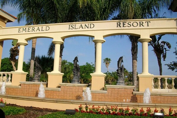 A sign with 'Emerald Island Resort' written across it, flanked by columns and statues.