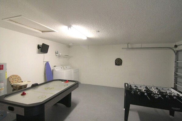 Una habitación con mesa de futbolín, mesa de billar y dardos.