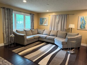 A living room with a sectional sofa, a striped rug, and a lamp.