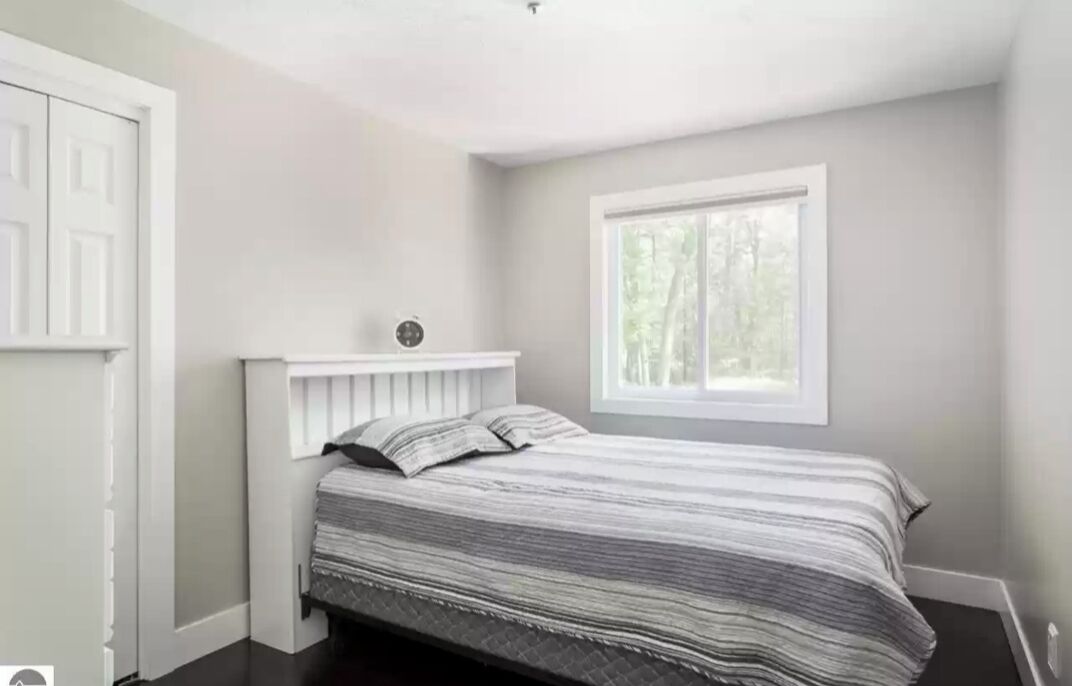 A bedroom with a bed, a window, and a door.