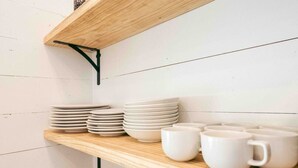 A kitchen shelf with stacked plates and cups. - Summer Haven | Swimming Hole + Farm Stay (Spring Branch)