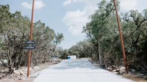 A road leading to a building with a sign reading "The Perchhaus The Nesthaus". - Summer Escape with Swim Hole and Golf Cart Rental (Spring Branch)