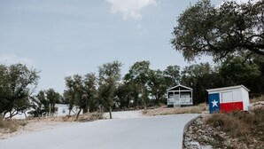 A small building with a porch, surrounded by trees and a clear sky. - Summer Escape with Swim Hole and Golf Cart Rental (Spring Branch)