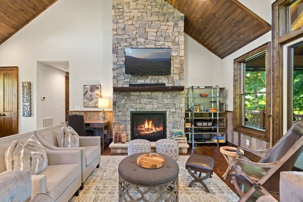 A cozy living room with a stone fireplace, comfortable seating, and a bookshelf.