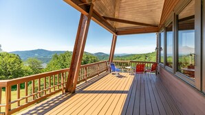 Eine Holzdielen-Terrasse mit Blick auf Berge und Bäume.