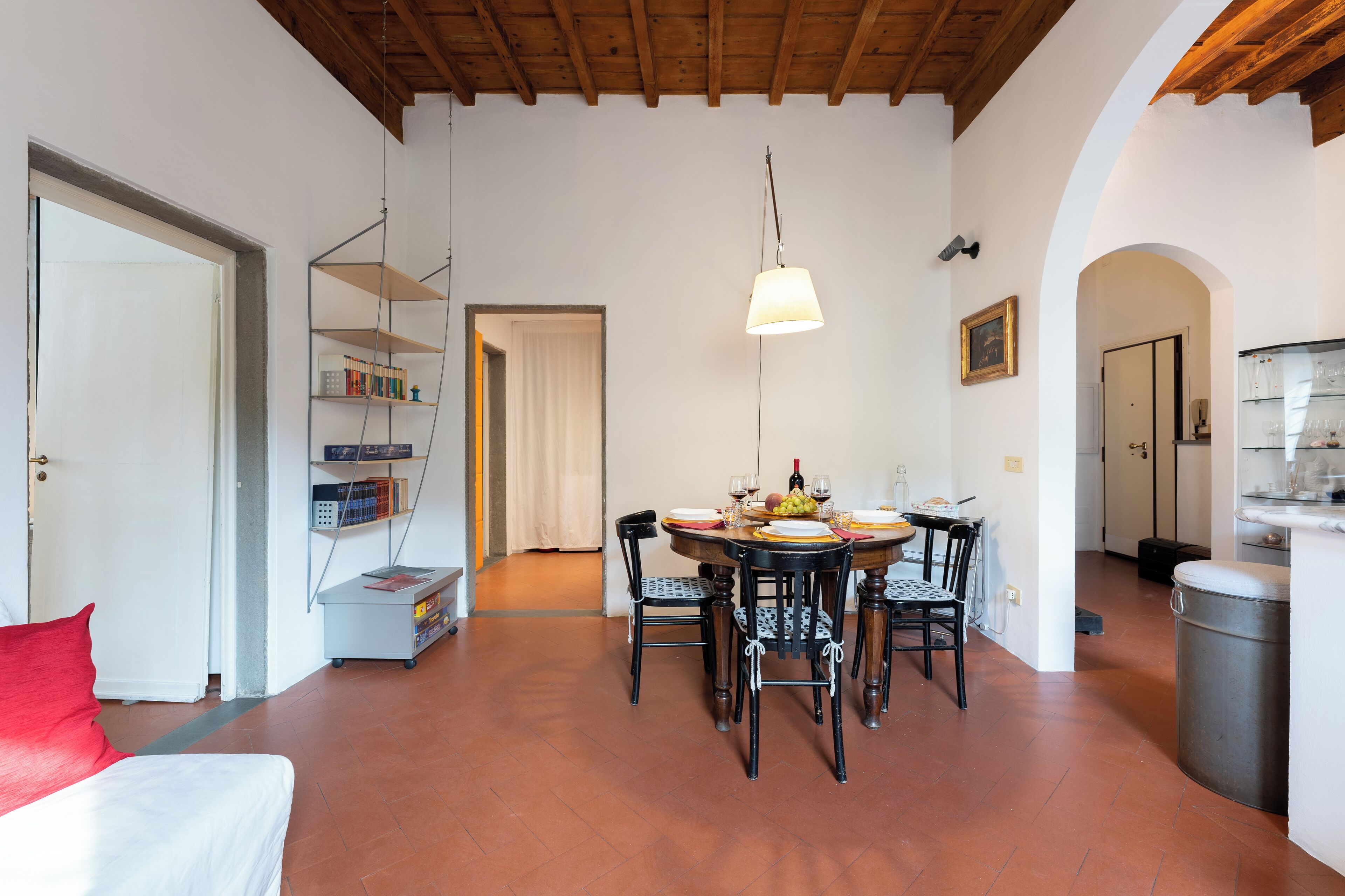 A dining area with a round table, chairs, and a hanging light fixture.