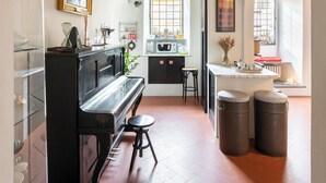 A narrow hallway with a wooden ceiling, a piano, a kitchen area with a microwave, and a window with a view. - Bombarde - Flo Apartments (Firenze)