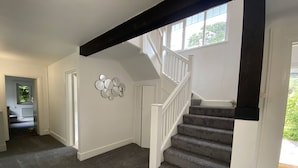 Eine Treppe mit dunklem Holzgeländer und Teppichboden, die zu einer Tür führt.