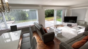 Ein modernes Wohnzimmer mit einer Couch, einem Couchtisch, einem Fernseher und einem Essbereich.