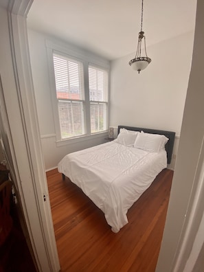 Cozy retreat with a single bed, large window, and hanging light fixture.