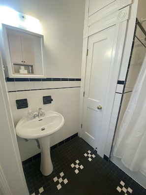 Bathroom features a pedestal sink, mirror, and shower area with a white curtain.