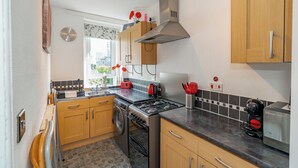 A modern kitchen with wooden cabinets, a stainless steel stove, and a coffee machine. - Home-from-home; 10 mins from city centre; Free on-street parking; Well-equipped (Edinburgh)