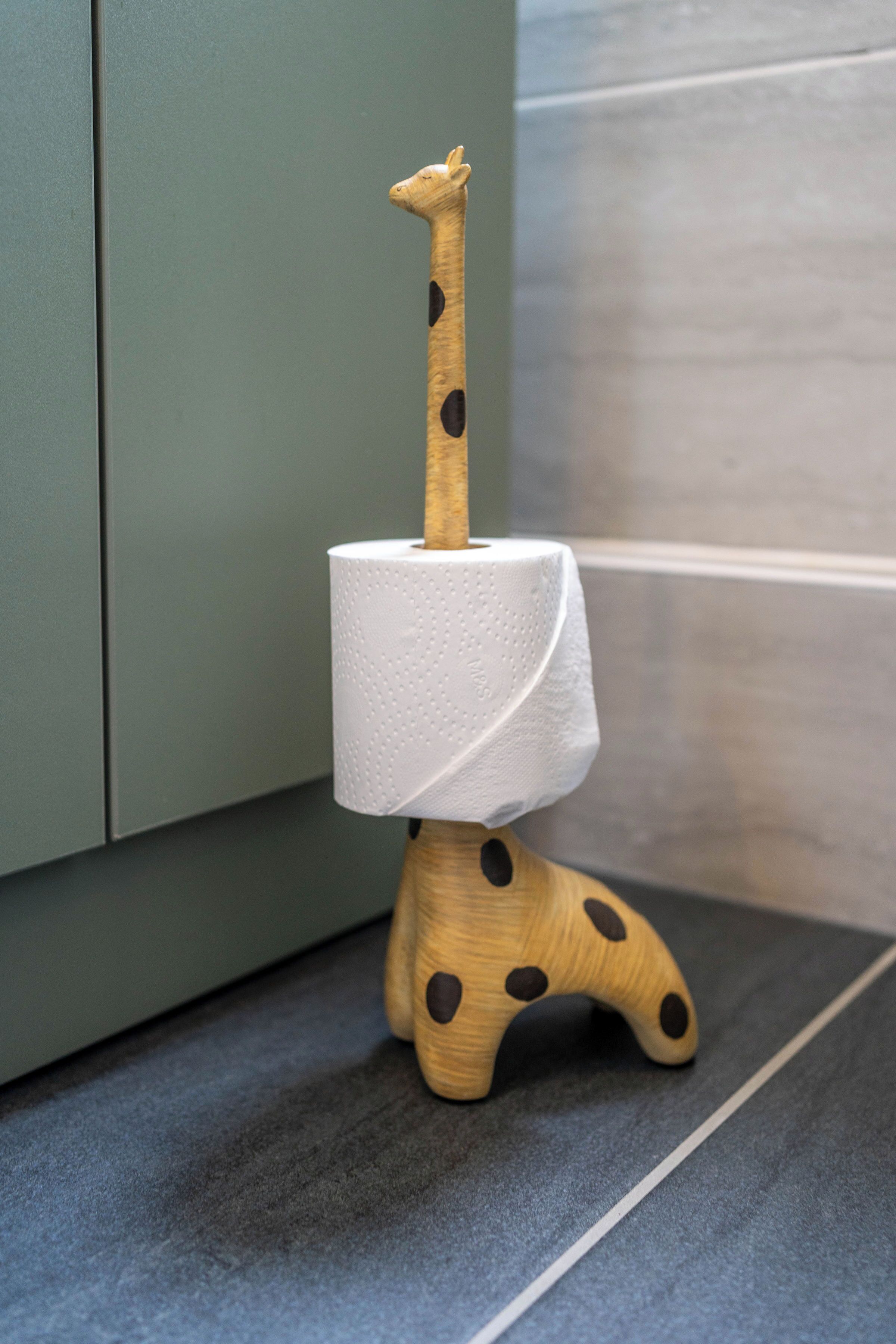 A giraffe-shaped toilet paper holder with a roll of toilet paper.