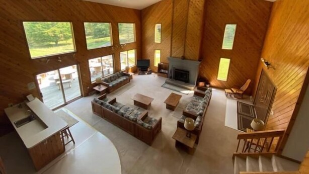 A spacious living area with a fireplace, large windows, and a staircase.