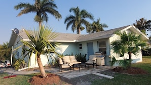A house with a patio, outdoor furniture, and palm trees. - Beautiful, cozy, clean & fresh house on a canal with private ramp, spce to moore (Bokeelia)