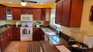 A kitchen with wooden cabinets, a white refrigerator, a microwave, and a stove. - Beautiful, cozy, clean & fresh house on a canal with private ramp, spce to moore (Bokeelia)