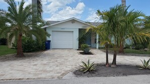 A residential property with a garage, palm trees, and a paved driveway. - Beautiful, cozy, clean & fresh house on a canal with private ramp, spce to moore (Bokeelia)