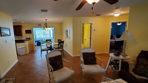 A spacious living room with a dining area, a kitchen in the background, and a yellow door leading to another room. - Beautiful, cozy, clean & fresh house on a canal with private ramp, spce to moore (Bokeelia)