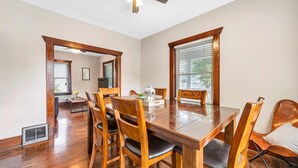 Comedor con mesa y sillas de madera, ventilador de techo y ventana con persianas.