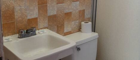 A bathroom with a toilet, sink, and green trash bin.