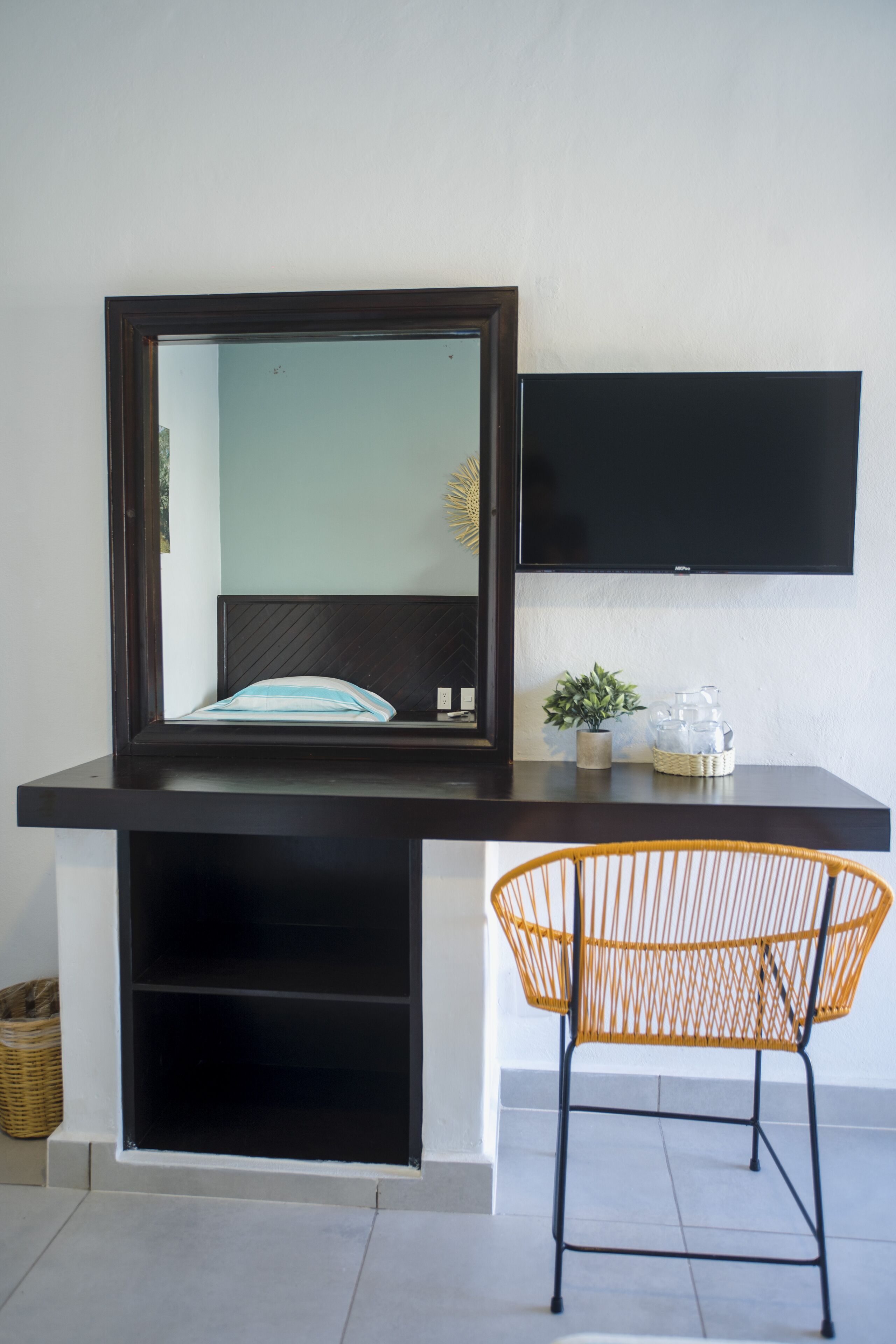 A modern room with a bed, a mounted TV, and a wicker chair.