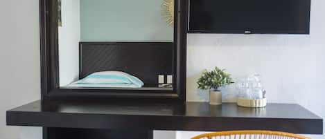 A modern room with a bed, a mounted TV, and a wicker chair.