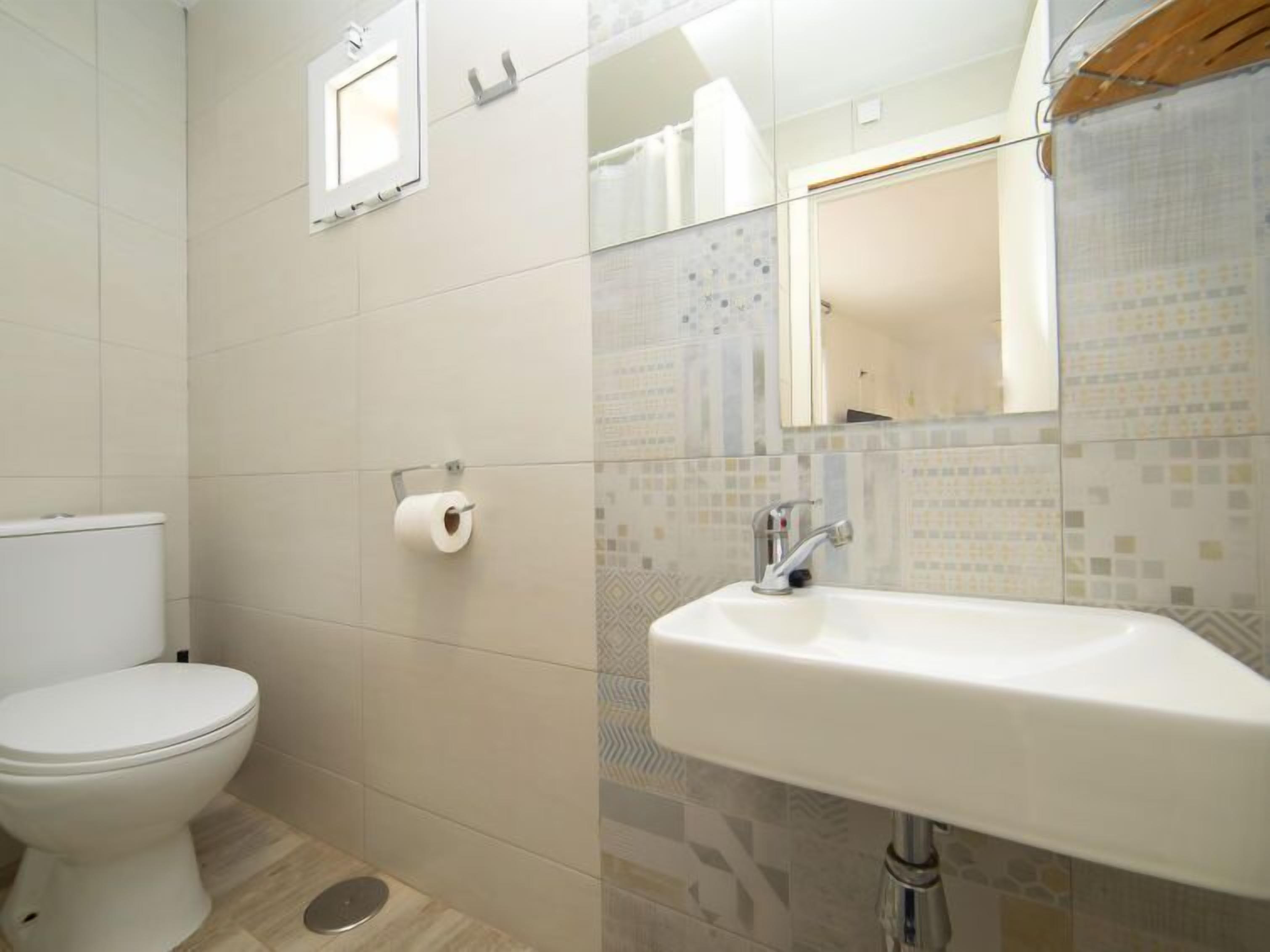 A bathroom with a toilet, a sink, and a mirror.