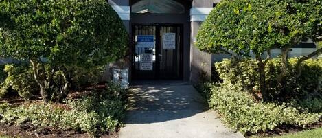 A building entrance with a no lifeguard on duty sign, a no parking sign, and a no trespassing sign.
