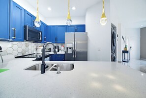 Une cuisine moderne avec des meubles bleus, des appareils en acier inoxydable et un îlot central doté d’un évier.