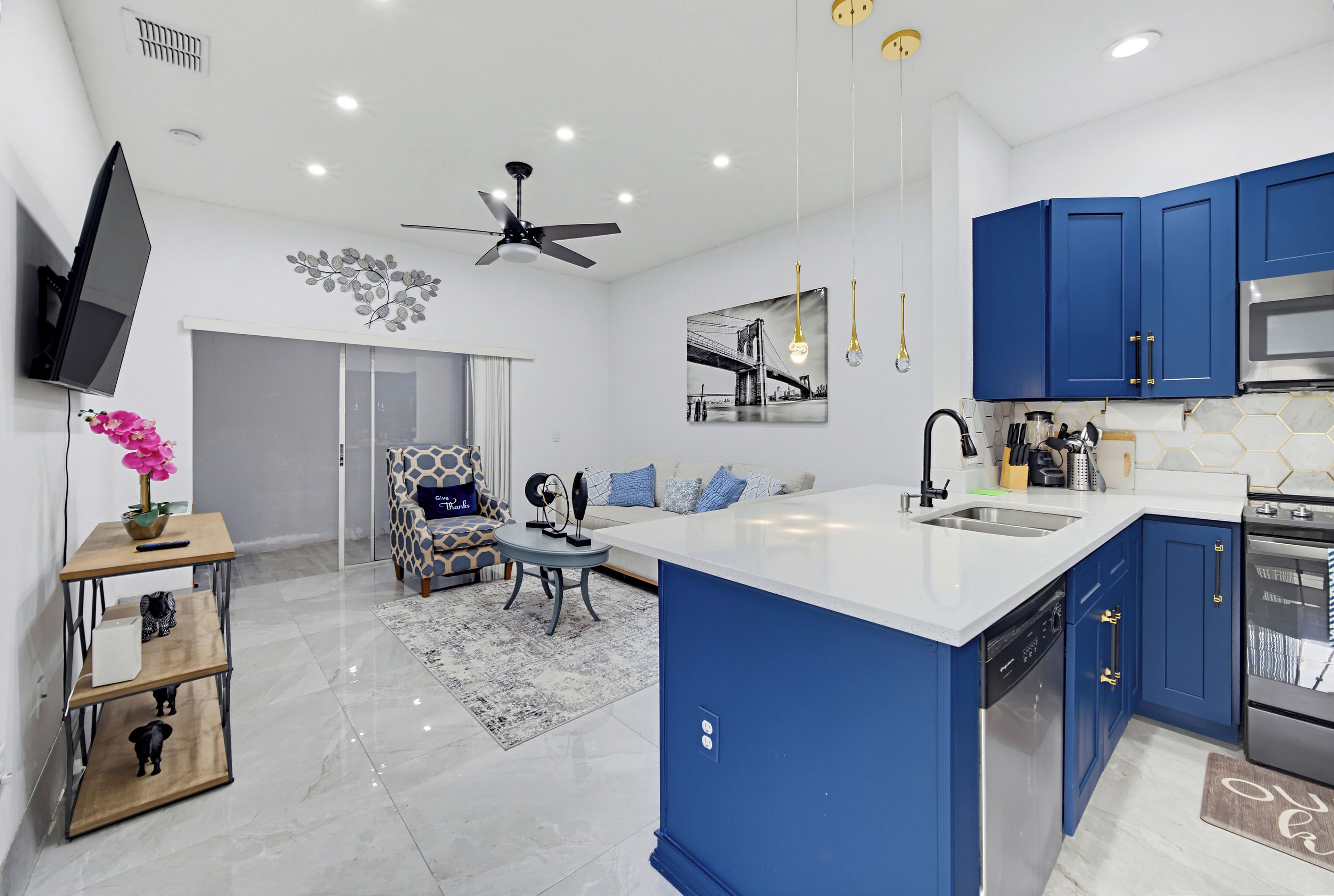 A modern kitchen with blue cabinets, a central island, and a dining area with a sofa and table.