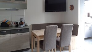 Une cuisine moderne avec un coin repas, comprenant des placards, une machine à café et un téléviseur à écran plat.