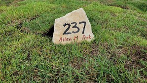 Une zone herbeuse avec un panneau indiquant : « 237, parc Allen M. ».