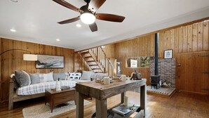 Un salón acogedor con suelo de madera, un sofá con cojines escoceses, una mesa de centro y una chimenea.