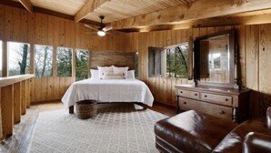 Un dormitorio de cabaña de madera con cama, cómoda y espejo grande.