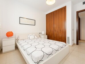 Ein Schlafzimmer mit einem Bett, einem Nachttisch, einem Holzschrank und einem gerahmten Bild an der Wand.