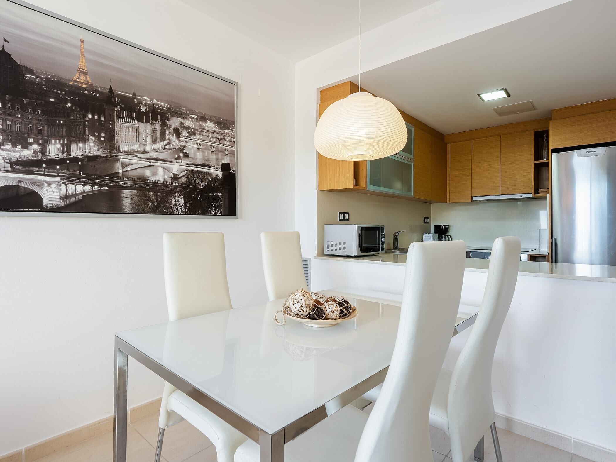 Une cuisine moderne dotée d’un îlot central, de meubles blancs et d’un luminaire suspendu.