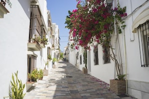 A narrow street with white buildings, balconies with plants, and a clear sky. - Sunset 10 Golf and Mountain, Marbella, Spain (Marbella)